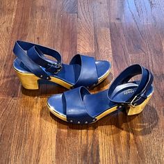 These Timeless Blue Peep-Toe Clogs Are Lovingly With A Cross-Over Leather Strap And A Classic Wood Heel. Gently Used Blue Sandals With Stacked Heel And Medium Width, Blue Closed Toe Sandals With Medium Width, Blue Casual Sandals With Wooden Heel, Casual Blue Sandals With Wooden Heel, Blue Medium Width Closed Toe Sandals, Blue Clogs With Rubber Sole For Spring, Blue Closed Toe Sandals Medium Width, Blue Platform Clogs For Summer, Blue Sandals With Stacked Heel And Round Toe