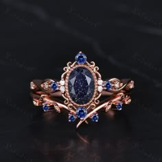 a fancy ring with blue sapphire stones and diamonds on it's sides, sitting on a black surface