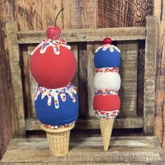 two ice cream cones with red, white and blue decorations on them sitting in a wooden crate