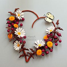 a heart shaped wreath with daisies, berries and butterflies on it that says good morning