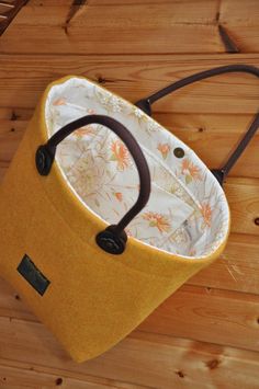 a handbag sitting on top of a wooden floor next to a brown bag with handles