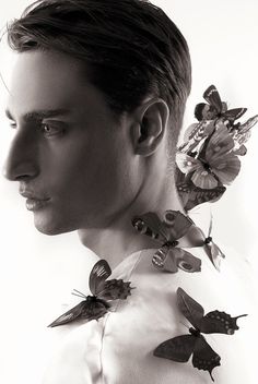 a man with butterflies on his neck in black and white, looking at the camera