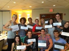 a group of people holding up signs in front of a room with tables and chairs