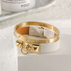 Sku: NSB1400GC-NSB1550STZD Details: Sleek and simple, this bracelet in leather with 14K gold plated. It is a statement-maker on its own or layered with other pieces. A great edition to an urban look or an informal outfit. This 14K gold/rose gold PVD bangle embellished with clear five of our best CZ stones. Arranged in an attractive and pleasing pattern, they catch the light from every angle. Our beautiful pieces are made of a metal that is hypo-allergenic which is great for those with sensitive Luxury Metal Bracelets With Gold-tone Hardware, Elegant Adjustable Bracelets With Gold-tone Hardware, Elegant Adjustable Bracelet With Gold-tone Hardware, Modern Adjustable Bracelets With Gold-tone Hardware, Modern Bracelets With Gold-tone Hardware, Luxury Gold Leather Bracelets, Elegant Gold-tone Bangle Bracelets, Adjustable Gold Bracelets With Gold-tone Hardware, Elegant Leather Bracelet With Gold-tone Hardware