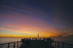 people standing on a pier watching the sunset