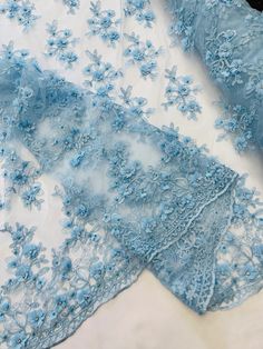 two pieces of blue lace with flowers on the bottom and one piece of sheer fabric