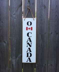 a sign hanging on the side of a wooden fence that says o canada with a maple leaf