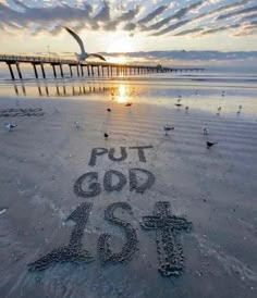 the words put god in the sand with seagulls flying around