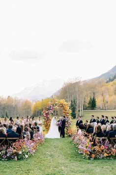 a wedding ceremony in the mountains with flowers and greenery on the aisle leading up to the bride and groom