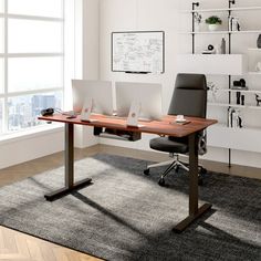 a desk with two laptops on it in front of a large window and bookshelf