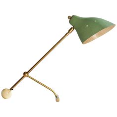 a green and gold desk lamp with a white ball on the arm, against a white background