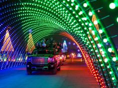 cars are driving down the road covered in christmas lights and decorated with green, red, and white lights