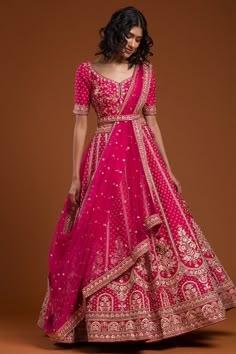 a woman in a pink lehenga with gold and red details on the skirt