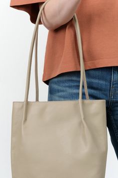 The Frances Bag is an elegantly designed shoulder bag featuring a soft form and an oval base, complemented by two rolled shoulder straps adorned with pinched details. Made from unlined vegetable-tanned semi-aniline cowhide, it offers a luxurious yet durable finish. This versatile accessory is ideal for everyday use, providing ample space to accommodate all your daily essentials with style and sophistication. Classic Tote Baguette Bag For Everyday Use, Beige Rectangular Shoulder Bag With Rolled Handles, Rectangular Beige Shoulder Bag With Rolled Handles, Everyday Double Handle Baguette Bag, Versatile Beige Bags With Rolled Handles, Modern Beige Bags With Rolled Handles, Daily Use Tote Baguette Bag With Handle Drop, Everyday Soft Leather Baguette Bag With Double Handle, Everyday Use Soft Leather Baguette Bag With Double Handle