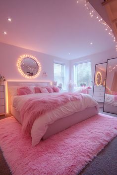 a bedroom decorated in pink and white with lights on the ceiling, rugs and bedding