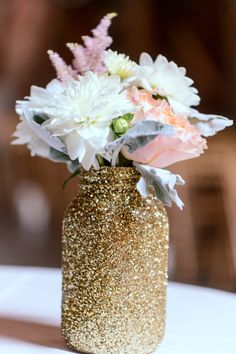 a vase filled with white and pink flowers on top of a table next to a sale sign