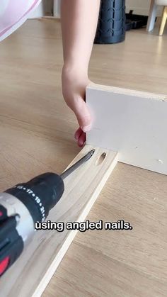 a person using an angleed nailer to cut wood planks on the floor