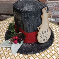 a black hat with a red ribbon around it and a wooden ornament hanging from the top