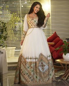 a woman in a long white dress posing for the camera with her hand on her hip