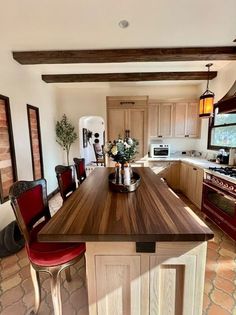 a kitchen with an island in the middle and red chairs at the counter top,