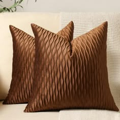 two brown pillows sitting on top of a white couch