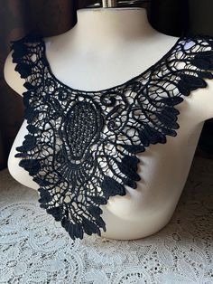 a white mannequin with black crochet lace on it's neck