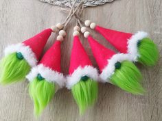 four green and white elf hats on top of a wooden table next to an ornament