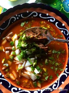 a bowl filled with soup on top of a blue and orange plate next to a spoon