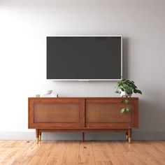 a flat screen tv mounted to the side of a wooden cabinet in an empty room