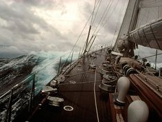 the back end of a boat sailing in rough seas on a cloudy day with strong waves