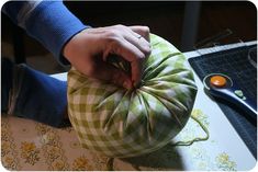 a person is sewing on a green and white pillow