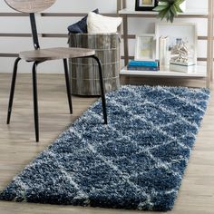 a blue area rug in a living room next to a chair and table with pictures on the wall