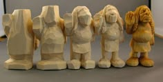 five carved figurines are lined up in a row