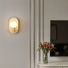 a vase filled with flowers sitting on top of a table next to a wall light