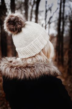 a person wearing a white hat with a fur pom - pom on it