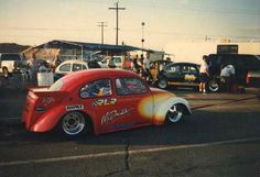 an old car with flames painted on it's side in a parking lot next to other cars