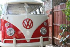 a red and white vw bus parked next to a wooden fence