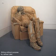 a man is sitting in a chair made out of cardboard and paper mache, with his feet propped up against the wall