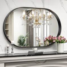 a mirror sitting on top of a mantle next to a vase filled with flowers