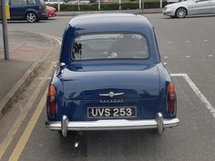 an old blue car is parked on the side of the road