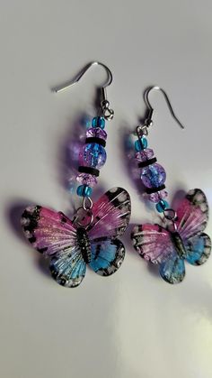 three purple and blue butterflies hanging from earrings