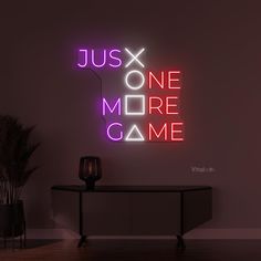 a neon sign that says just one more game on the wall next to a table