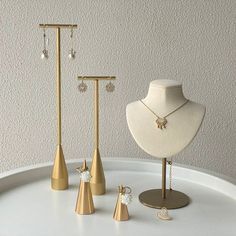 three necklaces and two earring stands on a table