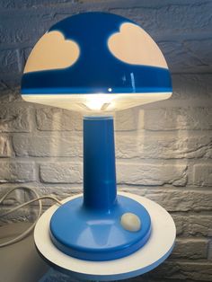 a blue and white lamp sitting on top of a table next to a brick wall