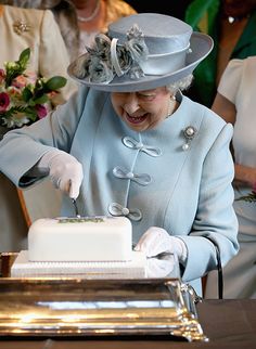 the queen is smiling as she cuts her cake