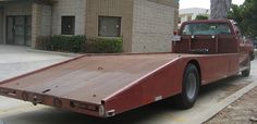 a red flatbed truck parked in front of a building