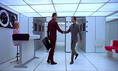 two people shaking hands in a room with red chairs and lockers on the walls