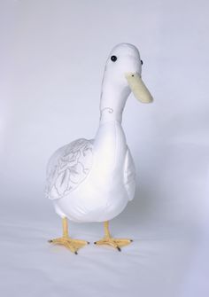 a white duck with yellow feet standing in front of a white background and looking at the camera