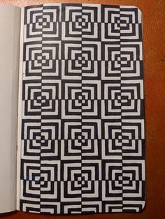 an open book with black and white squares on it's cover sitting on a table