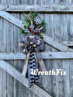 a christmas bow hanging on the side of a wooden door with pine cones and berries